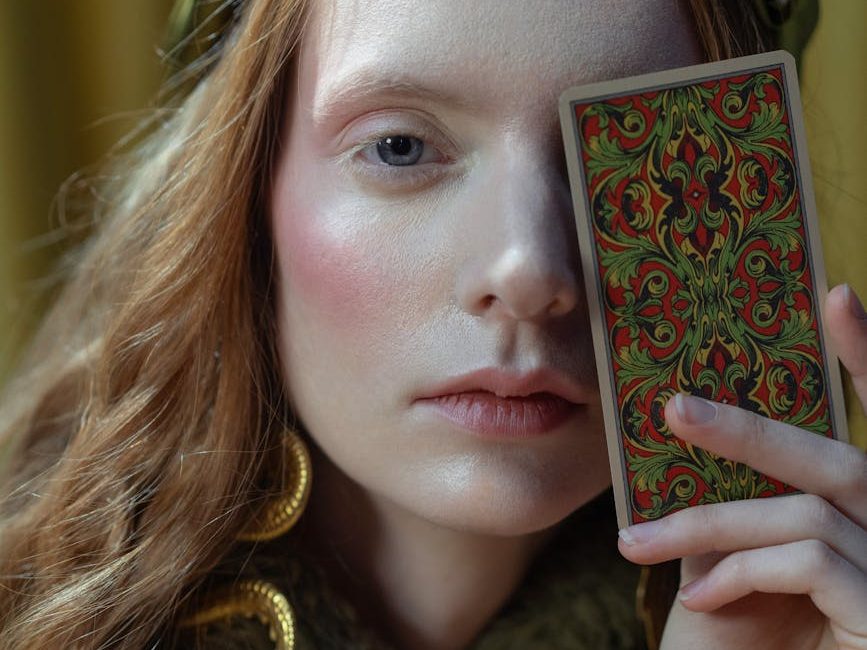 Woman holding tarot card over her left eye