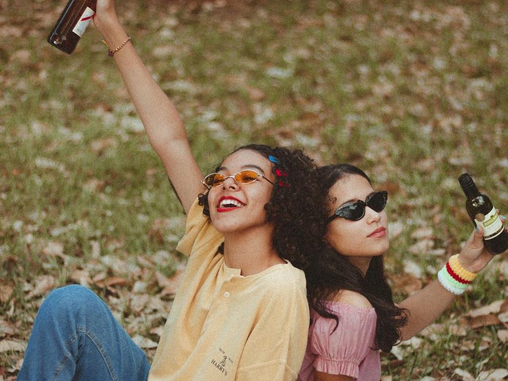 two friends with opposite vibes holding beer bottles