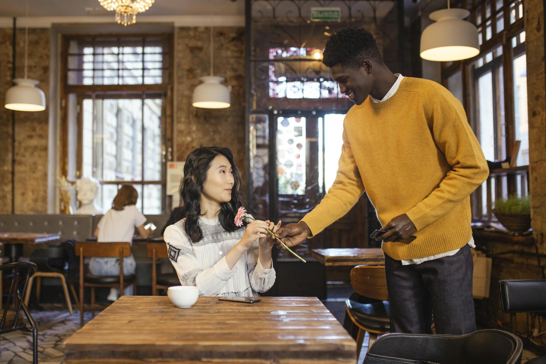 smiling man giving a flower to a woman on a first date